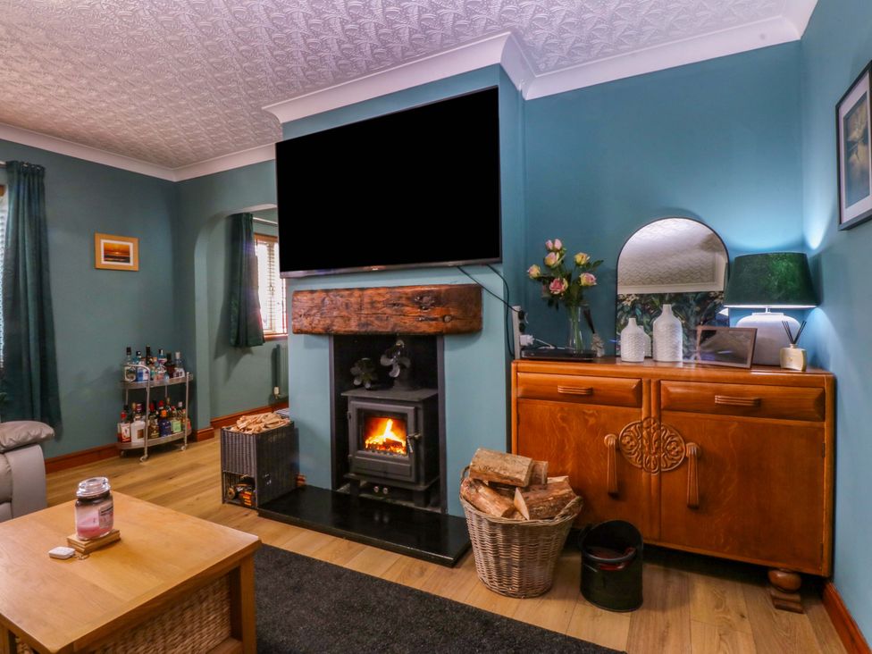 A living room with a fireplace and television at 36 Cae Rhos in Holyhead