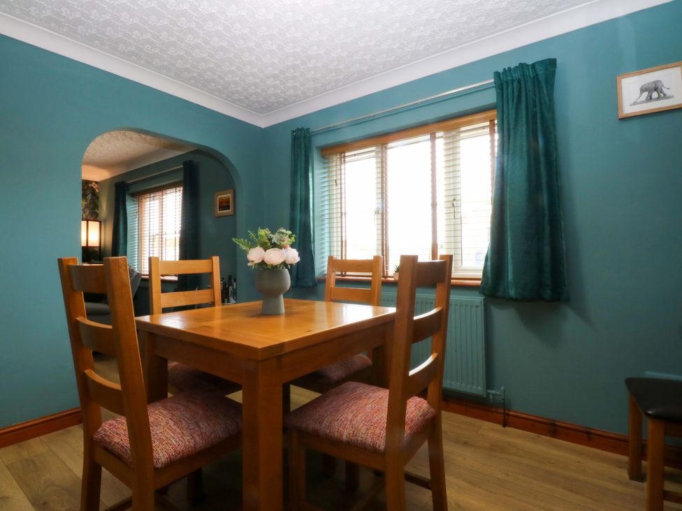 A dining room with a wooden table and chairs at 36 Cae Rhos in Holyhead
