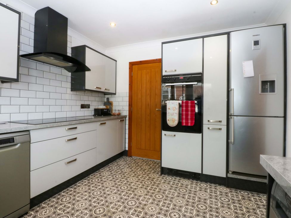 A kitchen with appliances and a door at 36 Cae Rhos in Holyhead