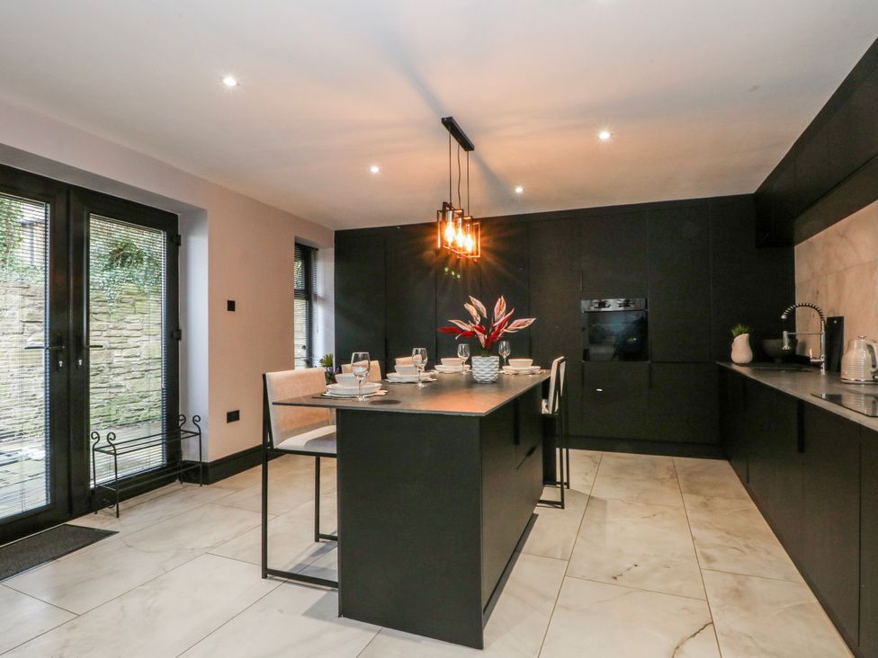 A kitchen with a counter and chairs at 2 Manor House farm Higher Ogden near Newhey