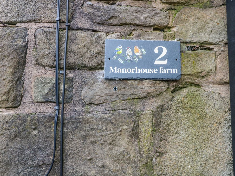 A house sign on a stone wall at Manorhouse farm in Higher Ogden near Newhey