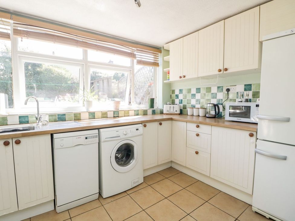 A kitchen with appliances and a window at Yewbarrow in Seascale