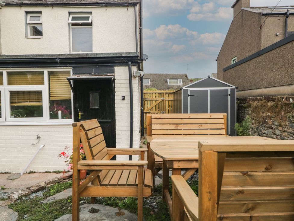 A garden with wooden furniture and a shed at Yewbarrow in Seascale