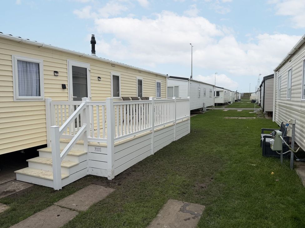 A caravan with a deck and steps at Chappie's Caravan Rhyl