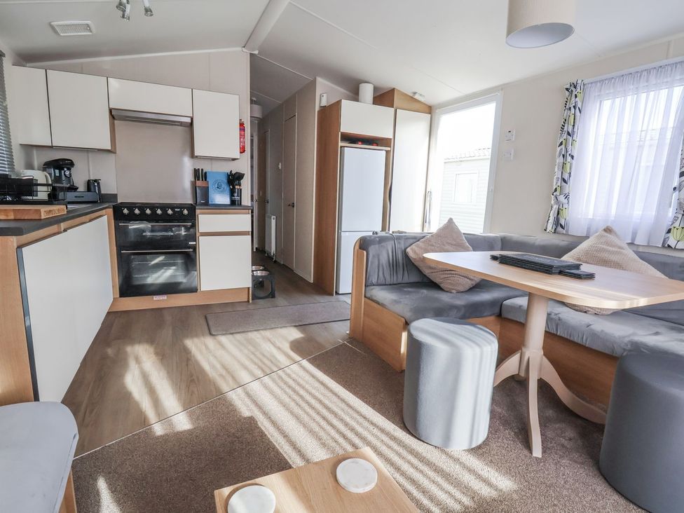 A living room with kitchen appliances and seating at Chappie's Caravan in Rhyl