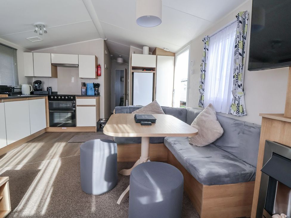 A kitchen and dining area with a sofa and table at Chappie's Caravan in Rhyl