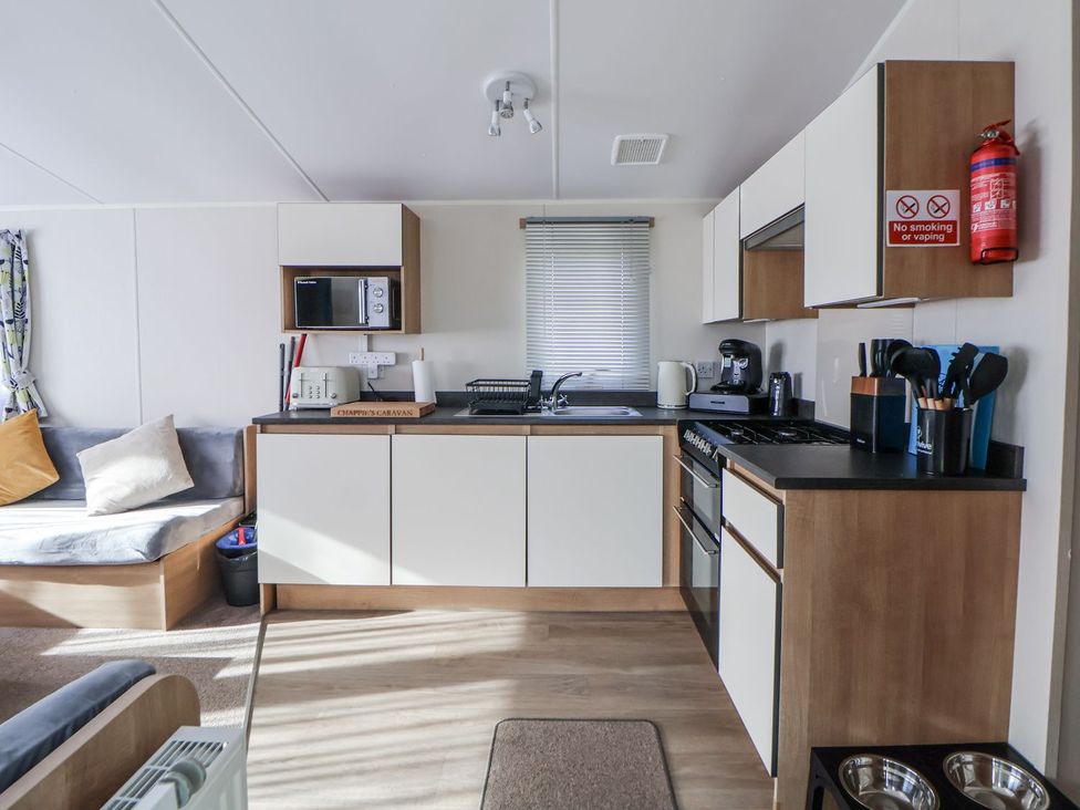A kitchen with a sofa and appliances at Chappie's Caravan in Rhyl