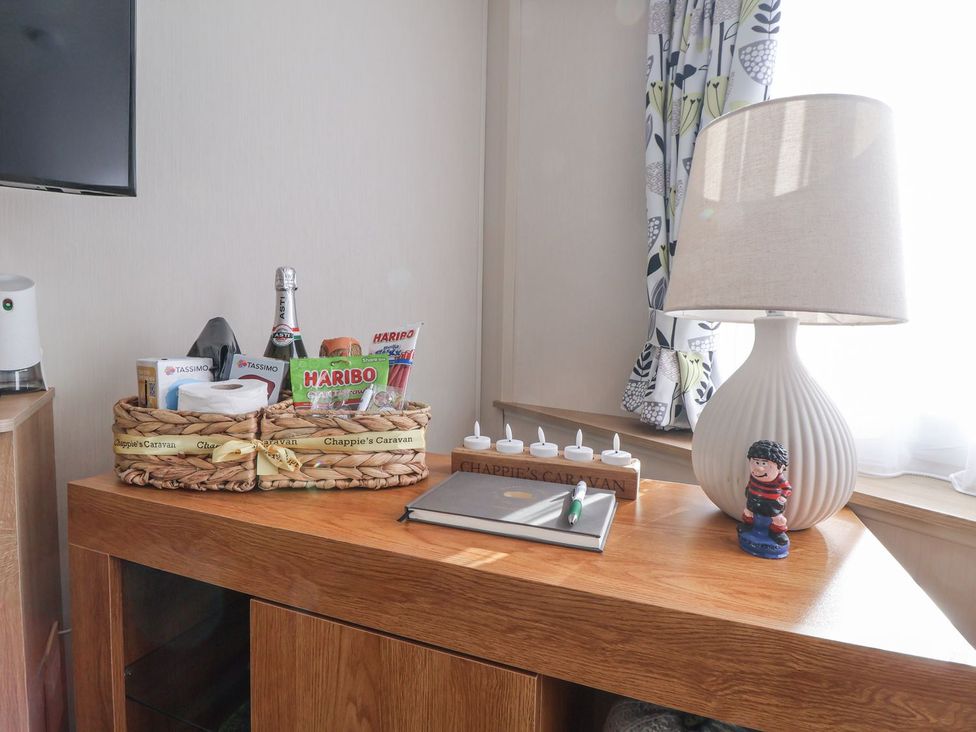 A living room with a basket and lamp at Chappie's Caravan in Rhyl