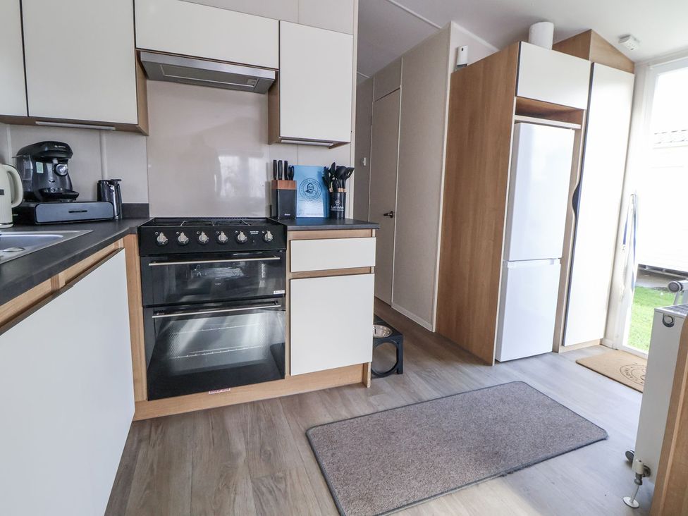 A kitchen with appliances and cabinets at Chappie's Caravan in Rhyl