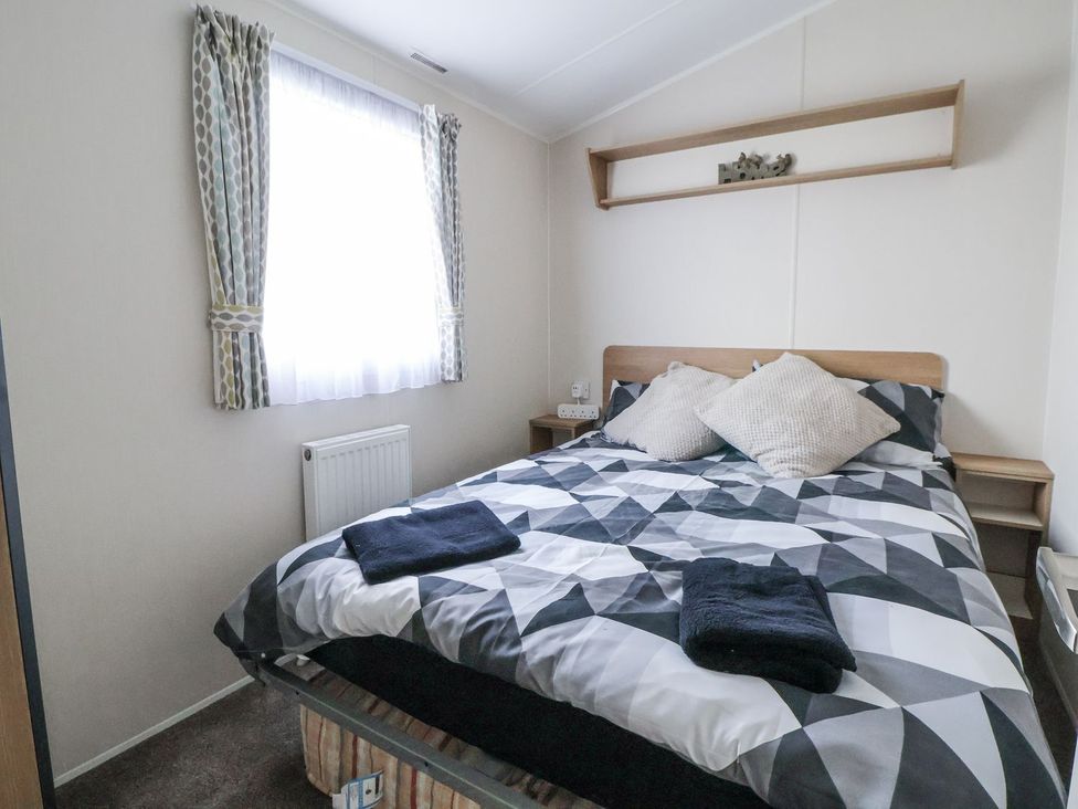 A bedroom with a bed and window at Chappie's Caravan Rhyl