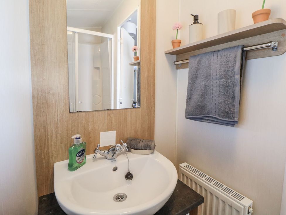 A bathroom with a sink and mirror at Chappie's Caravan in Rhyl