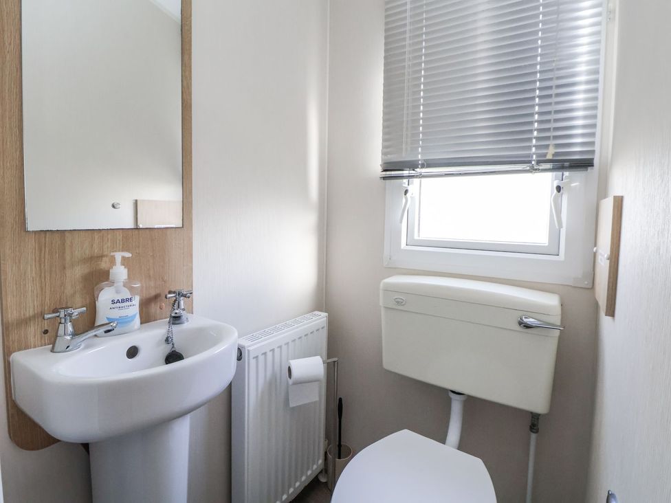 A bathroom with a sink and a toilet at Chappie's Caravan in Rhyl