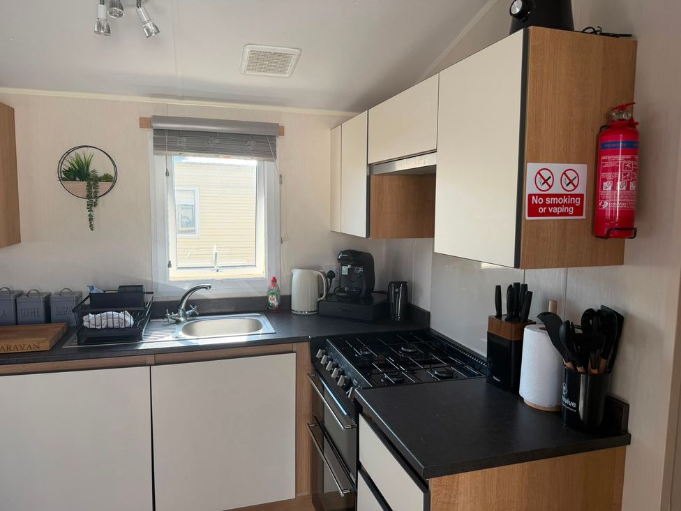 A kitchen with sink, stove, and cabinets at Chappie's Caravan 1.0 in Rhyl