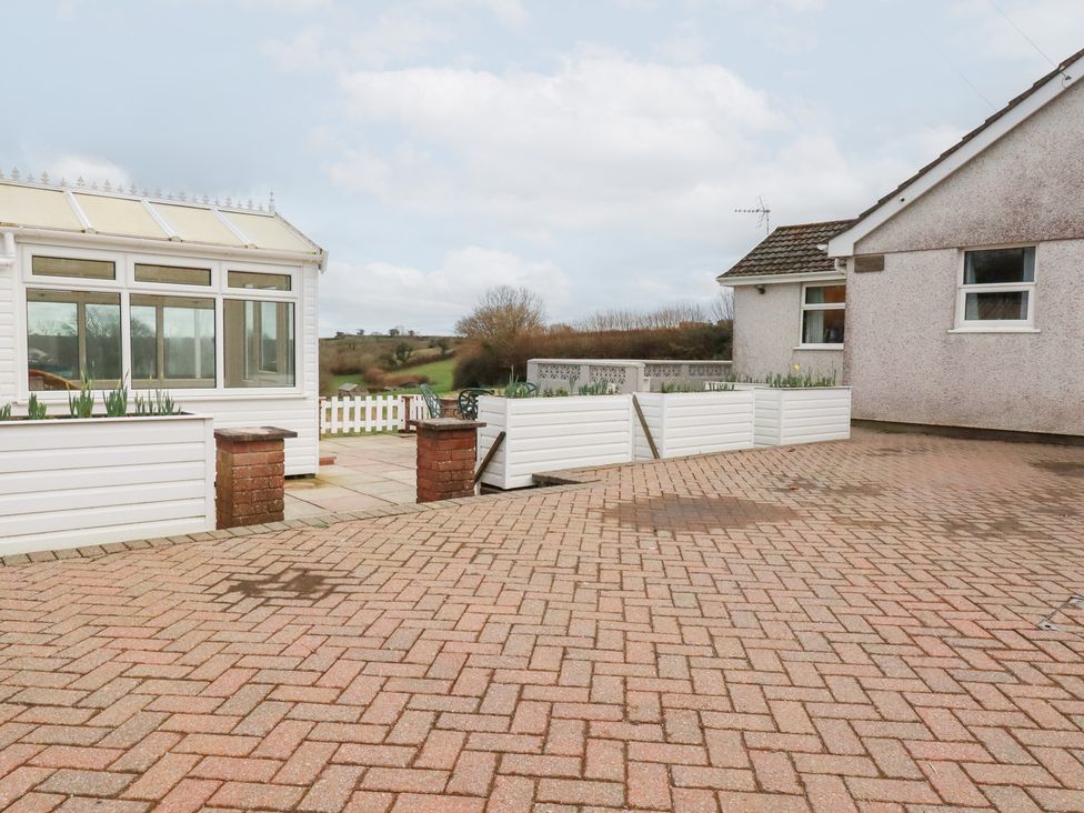 A garden with a conservatory and paved area at The Bungalow in St. Austell