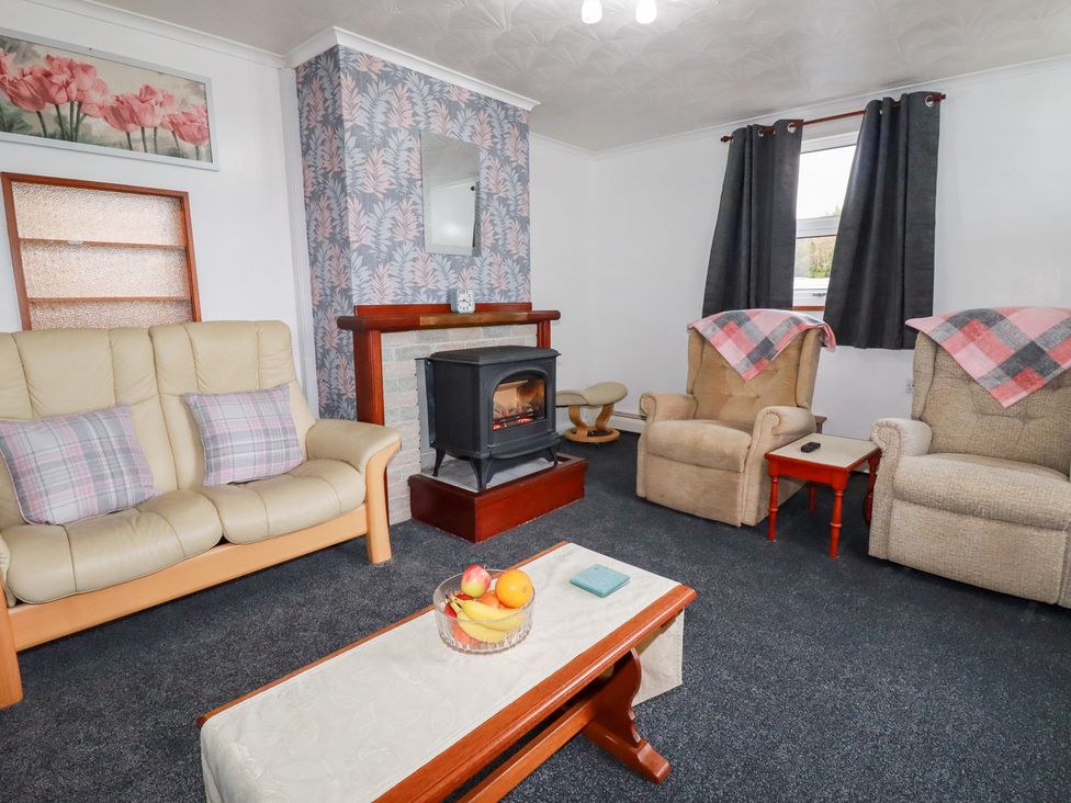 A living room with a fireplace and seating arrangements at The Bungalow in St. Austell