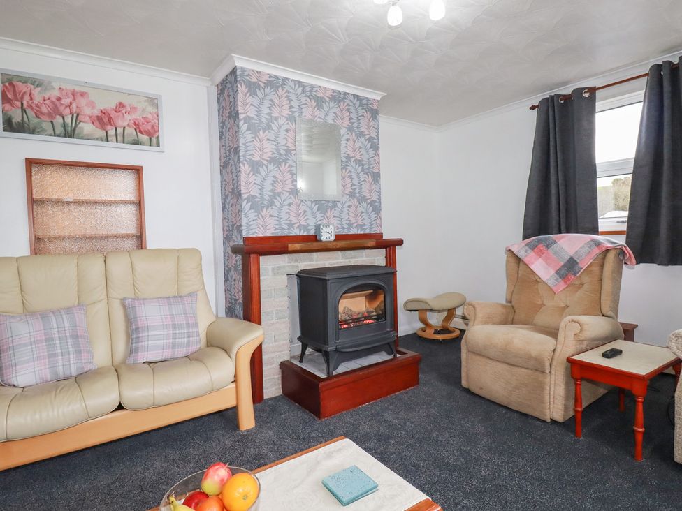 A living room with a fireplace and seating area at The Bungalow in St. Austell