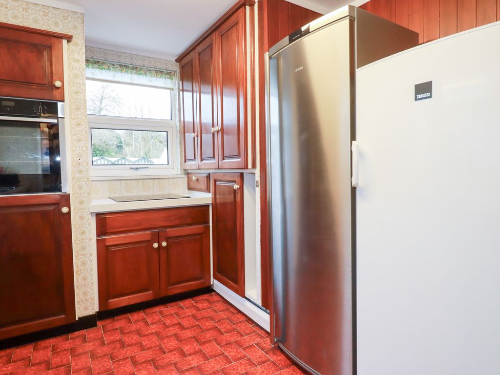 A kitchen with cupboards, an oven, a sink, and a fridge at The Bungalow in St. Austell