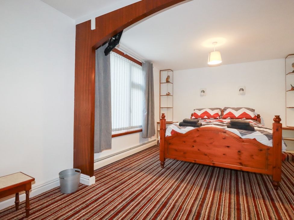 A bedroom with a wooden bed and shelves at The Bungalow in St. Austell