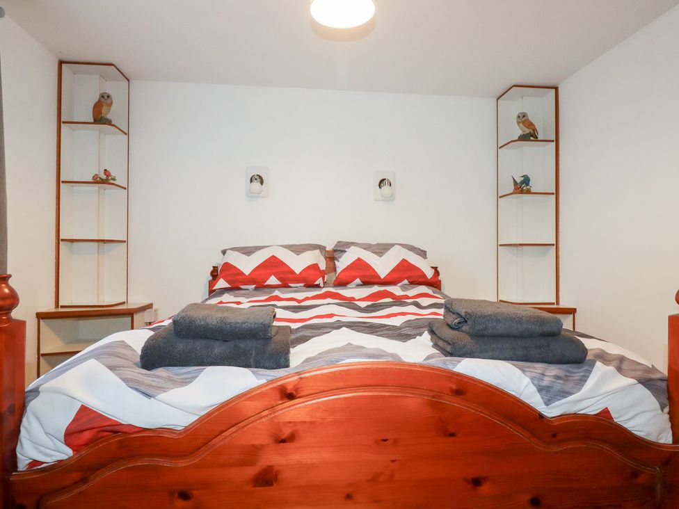 A bedroom with a bed and towels on top at The Bungalow in St. Austell