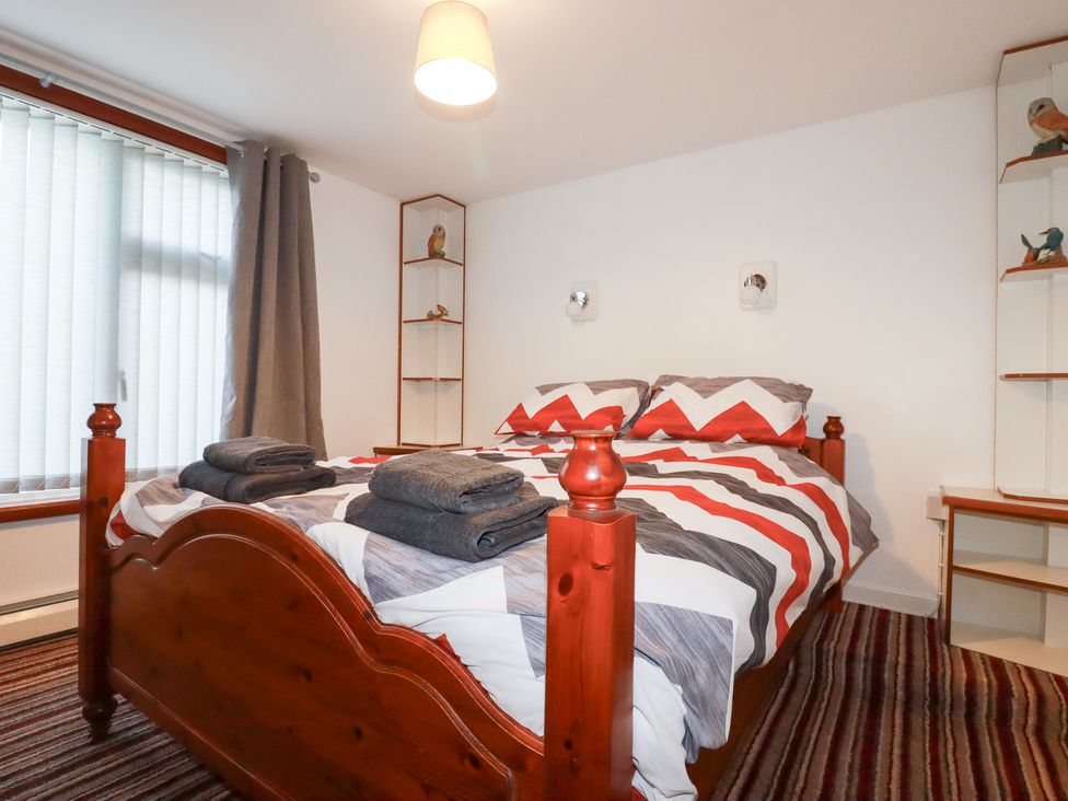 A bedroom with a bed and shelves at The Bungalow in St. Austell