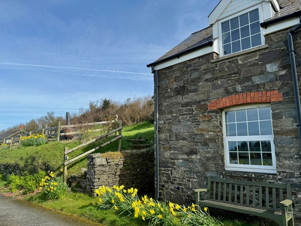 A stone house with a window and flowers in a garden at Penpegws near Aberystwyth