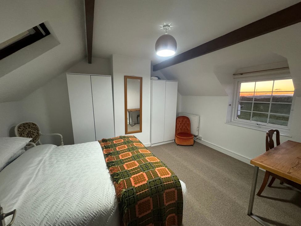A bedroom with a bed, wardrobe, chair, and window at Penpegws near Aberystwyth