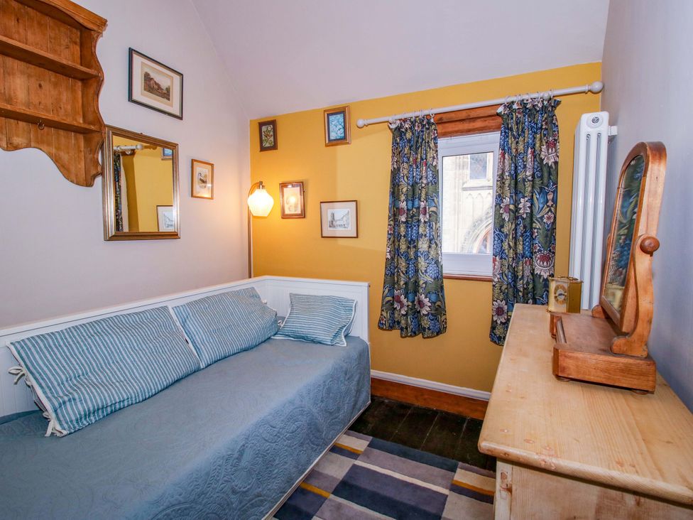 A bedroom with a sofa and dresser at Katie's Cottage in Church Stretton