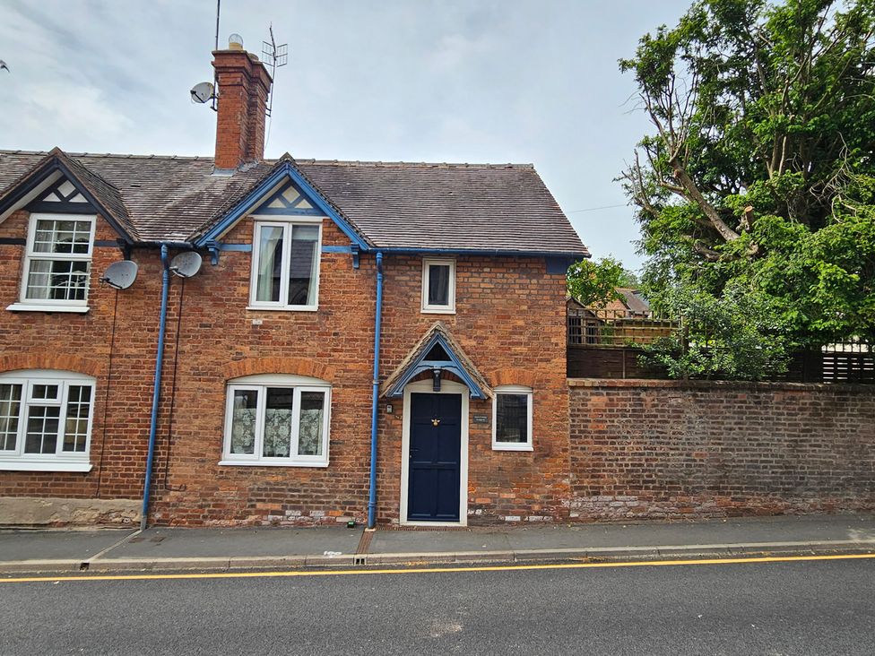A brick house with a blue door and white windows at Katie's Cottage in Church Stretton