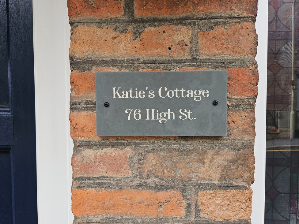 A nameplate on a brick wall at Katie's Cottage 76 High St