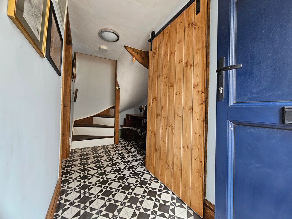 A hallway with a staircase and wooden doors at Katie's Cottage in Church Stretton