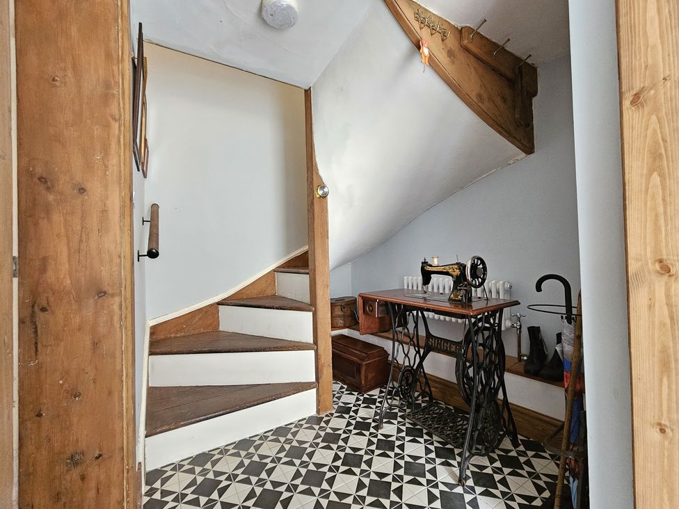 A staircase with a sewing machine and wooden rail at Katie's Cottage in Church Stretton