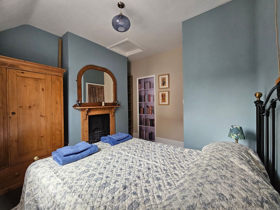 A bedroom with a bed and wardrobe at Katie's Cottage in Church Stretton