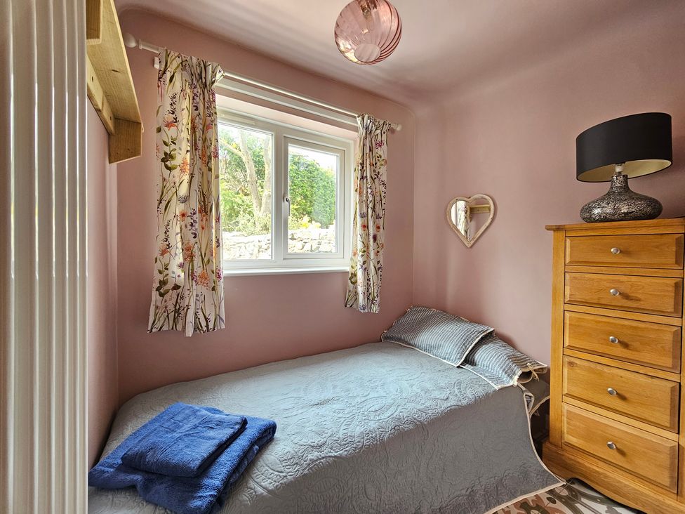 A bedroom with a bed and dresser at Katie's Cottage in Church Stretton