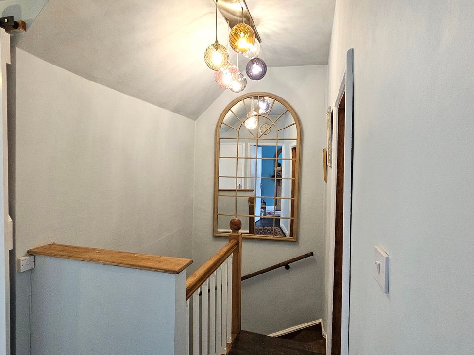 A hallway with a staircase and a light fixture at Katie's Cottage in Church Stretton