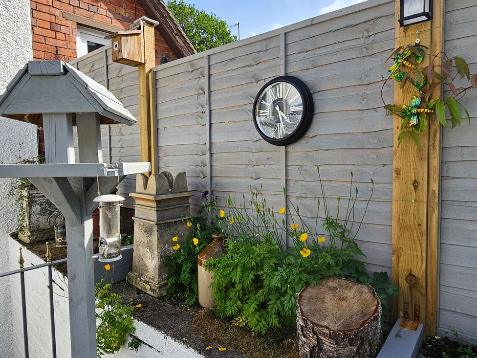 An outdoor area with a bird feeder and clock at Katie's Cottage in Church Stretton