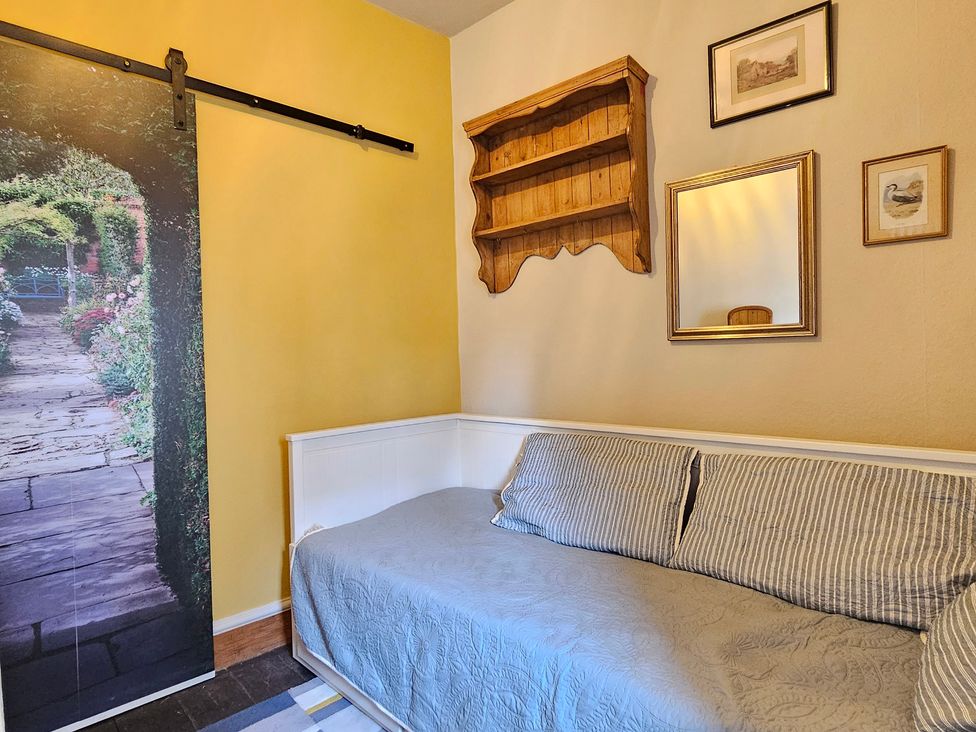 A guest room with a sofa and wall shelf at Katie's Cottage in Church Stretton