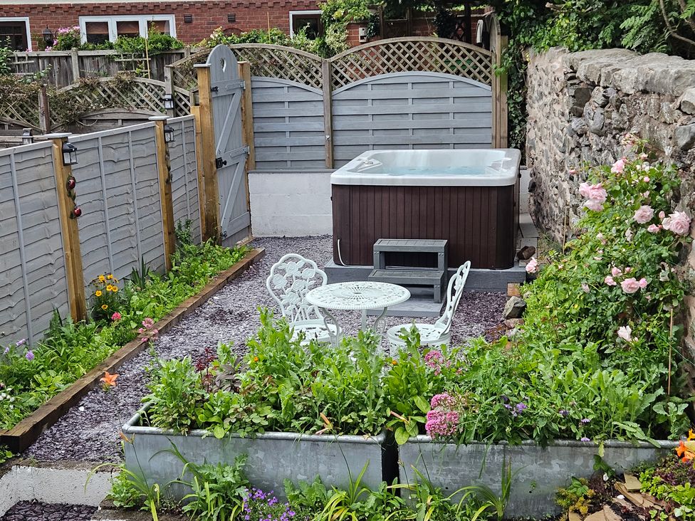 A garden with a hot tub and table set at Katie's Cottage in Church Stretton