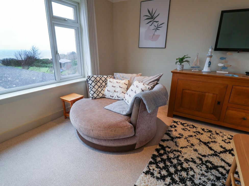 A living room with a round sofa and a side table at Cliff Cottage