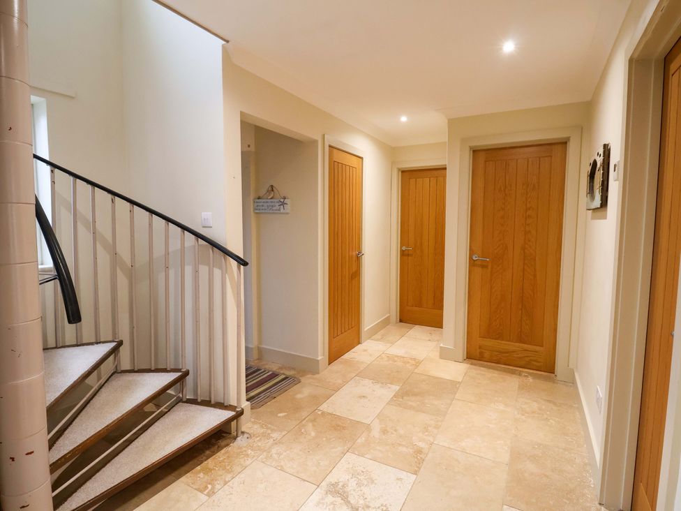 A hallway with a staircase and multiple doors at Cliff Cottage