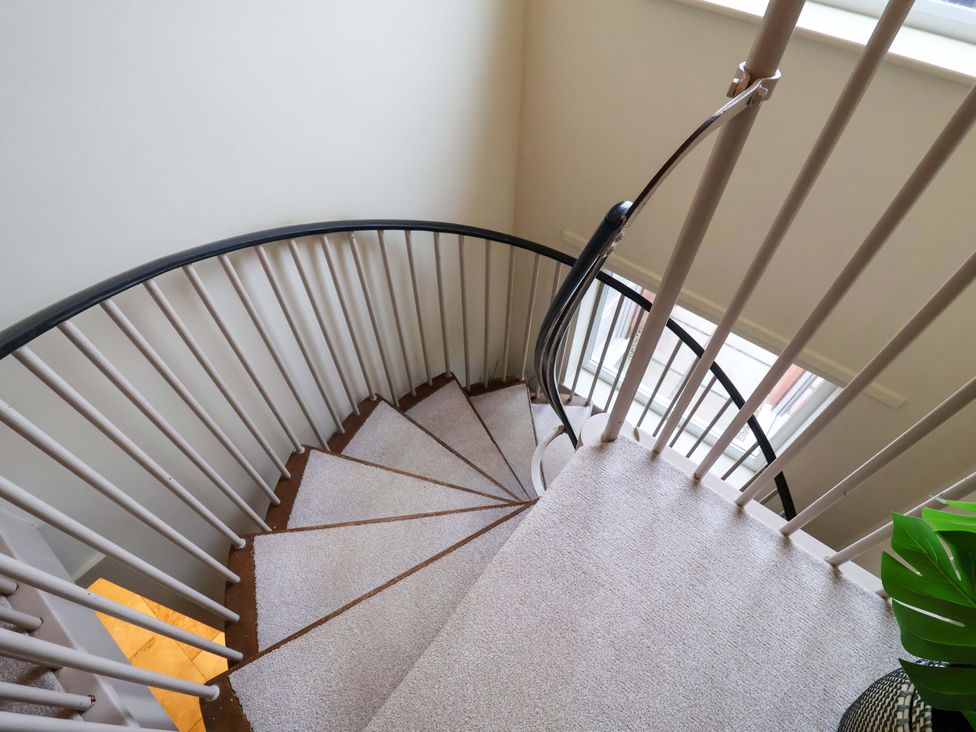 A spiral staircase with carpet and a window at Cliff Cottage