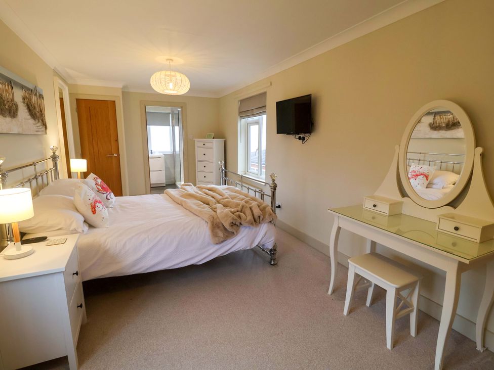 A bedroom with bed, dresser, and television at Cliff Cottage