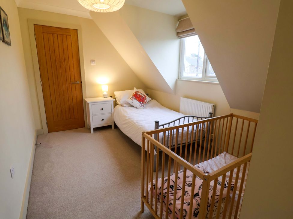 A bedroom with a bed and a crib at Cliff Cottage