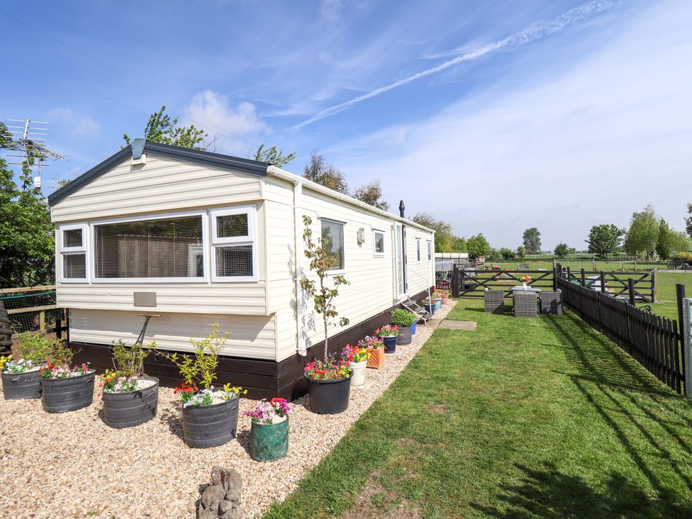 A mobile home with flower pots and a fenced garden at Ewe View 