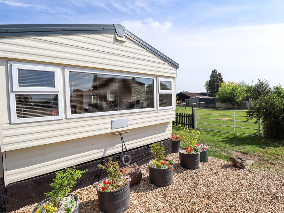 An exterior view of a mobile home with flower pots in the garden at Ewe View