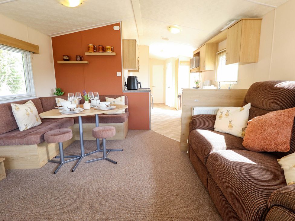 A living room with a dining area and kitchen cabinets at Ewe View