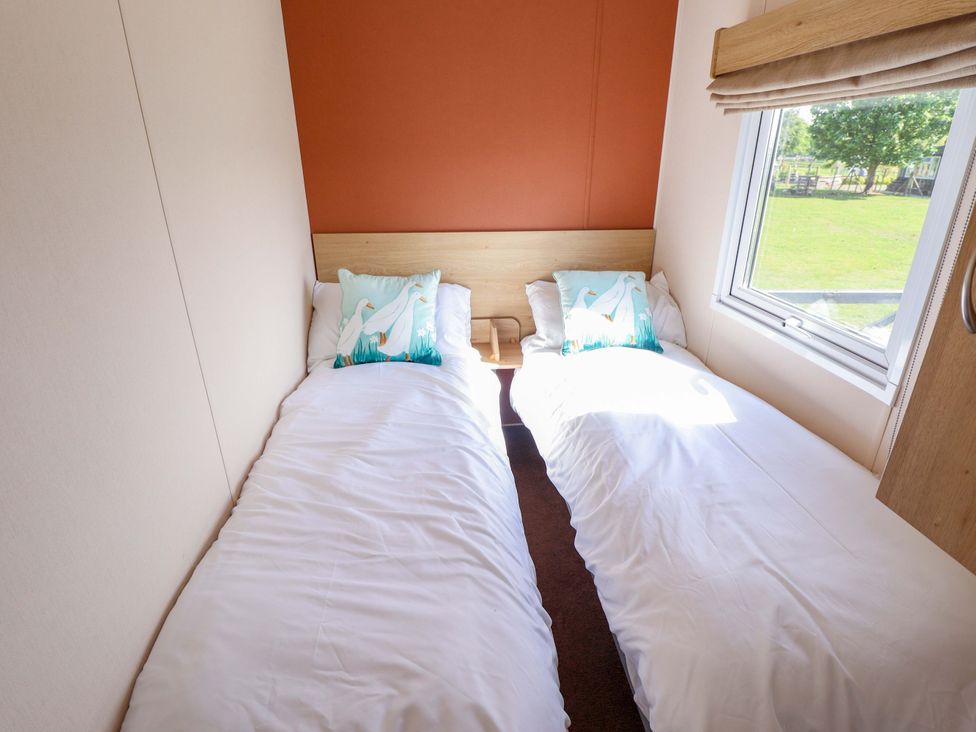 A bedroom with two single beds and a window at Ewe View