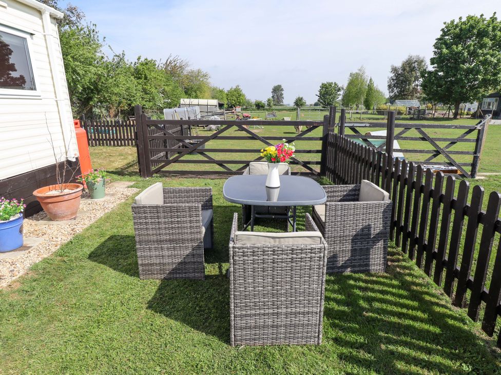 A garden with a table and chairs beside a fence at Ewe View