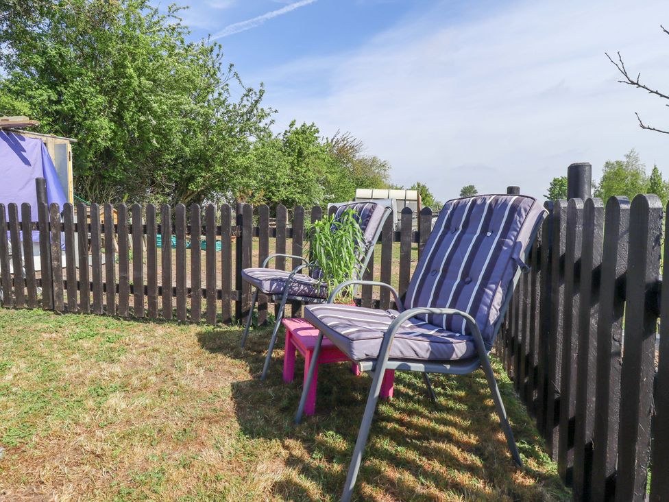 A garden with deck chairs and a wooden fence at Ewe View