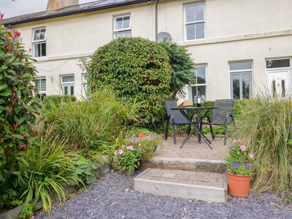A garden with a table and chairs surrounded by plants at 8 Railway Cottages in Ulverston