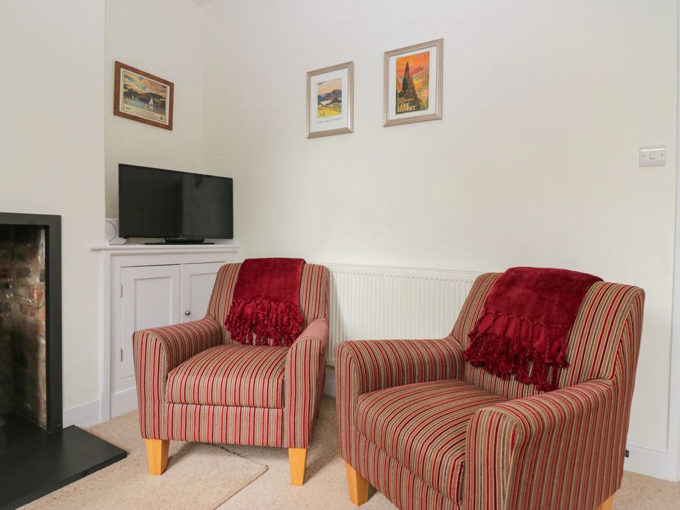 A living room with armchairs and a television at 8 Railway Cottages in Ulverston